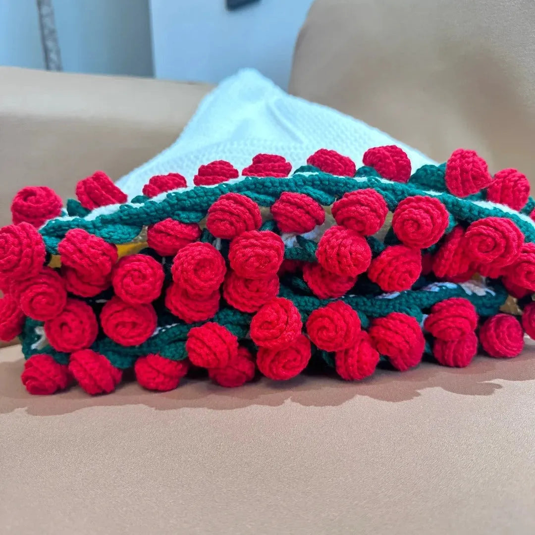Close-up of handmade crochet blanket edge with densely layered red roses and green stems